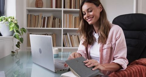 Smiling Woman in Minimalist Home Office Handling Journal