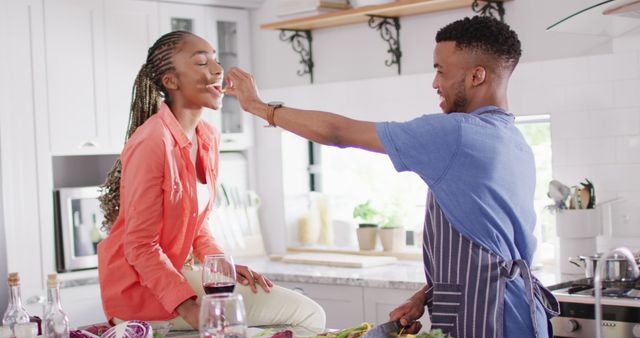 Happy african american couple preparing meal in kitchen and trying dish. Lifestyle, relationship, spending free time together concept.