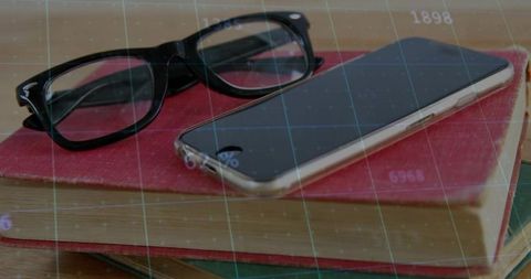 Smartphone and glasses on desk with grid overlay illustrates modern workspace