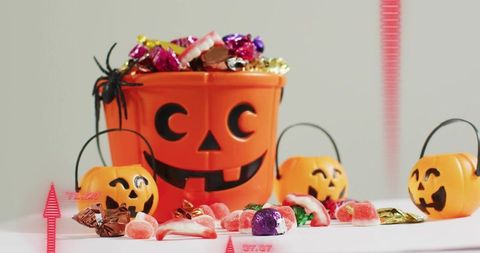 Halloween candy bucket overflowing with jack-o-lantern pails and colorful wrapped sweets