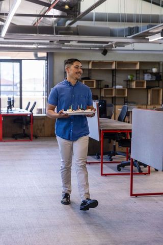 Office Worker Celebrating with Pastries in Modern Workspace