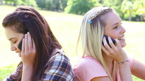 Happy Friends Relaxing in Park Having Cellular Conversations