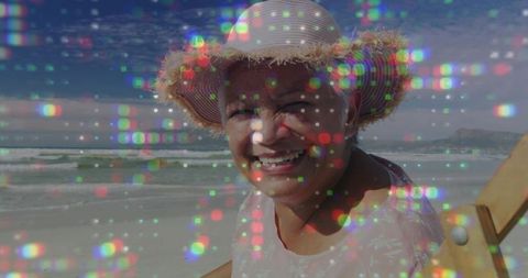 Senior woman relaxing on beach in straw sun hat