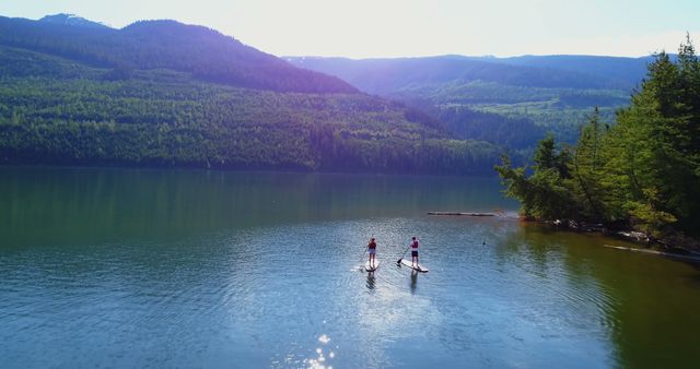 Aerial View of Couple Paddleboarding on Serene Lake Surrounded by Mountains - Download Free Stock Images Pikwizard.com