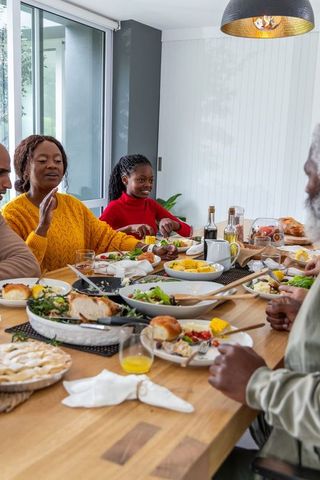 Multigenerational african american family sharing homemade meal around wooden dining table