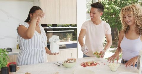 Joyful Friends Cooking Pizza in Modern Kitchen Setting