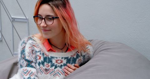 Young Woman with Glasses Sitting on Urban Pouf