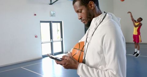 Basketball Coach with Smartphone in Gymnasium Preparing Sportswear - Download Free Stock Images Pikwizard.com