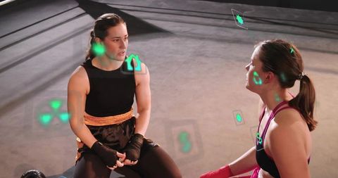 Female boxers discussing tactics with holographic overlays in boxing ring during training
