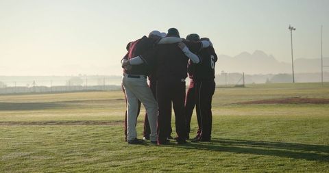Baseball teammates huddling on morning field showing unity