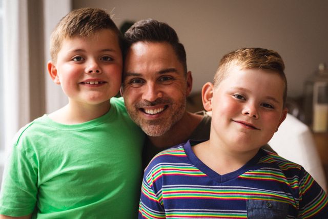 Father and two sons smiling together indoors. Perfect for family-oriented advertisements, parenting blogs, and articles about fatherhood and family bonding.
