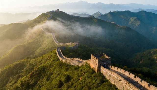 Sunlit great wall of china winding along misty mountain ridges at sunrise