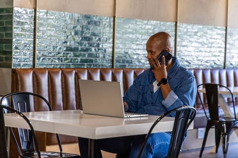 Working remotely in cafe with laptop and smartphone, freelance professional using mobile
