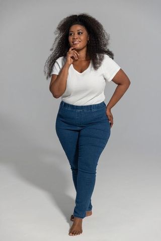 Confident african american woman barefoot in jeans and white top studio portrait