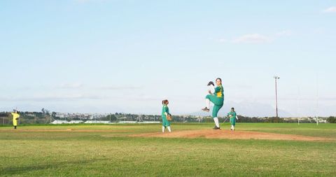 Female softball team practicing pitching on grass diamond
