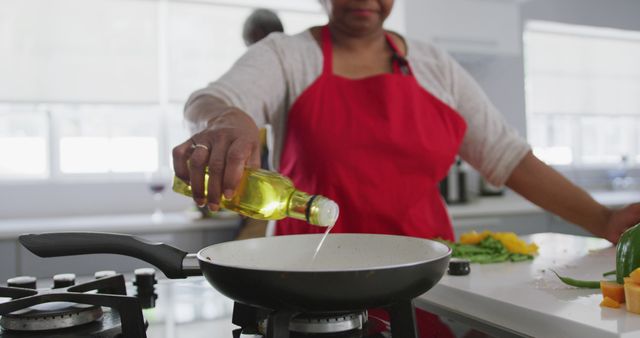 Senior Woman Cooking in Kitchen, Adding Oil to Frying Pan - Download Free Stock Images Pikwizard.com