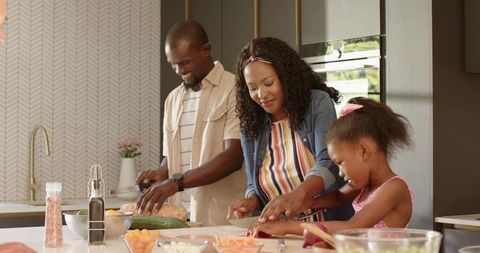 African American Family Cooking Together on Kitchen Island Chopping Fresh Vegetables