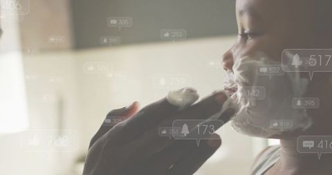 Parent applying shaving foam to child's face with floating social media notifications