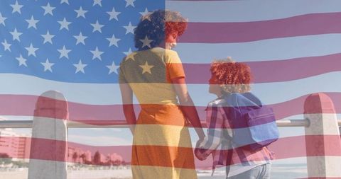 Mother and child holding hands at seaside with american flag overlay, patriotic moment