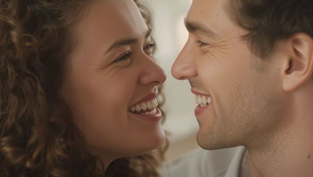 Smiling couple leaning foreheads together sharing intimate laugh closeup warm romance
