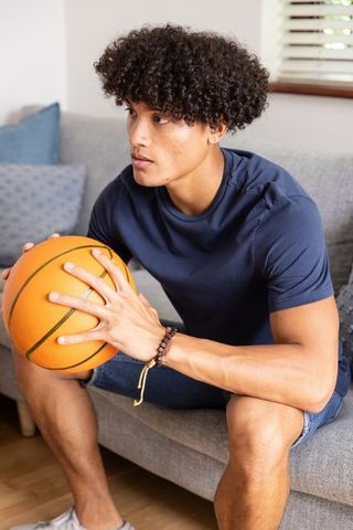 Young Athletic Man Holding Basketball Indoors