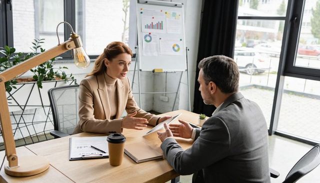 Business professionals discussing strategy over tablet, gesturing in modern office meeting