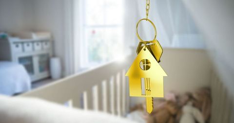 Gold house keychain with key in softly lit nursery crib
