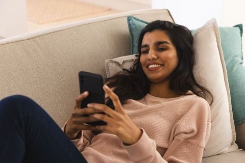 Smiling woman relaxing on sofa in modern home interior