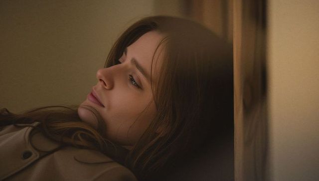 Reclining woman resting head against wooden panel, warm contemplative interior portrait