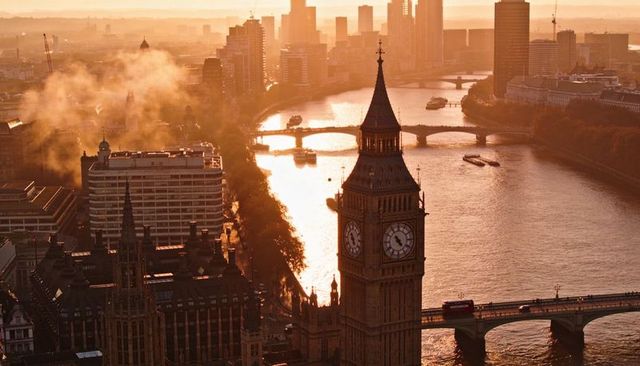 Golden sunset over river thames with elizabeth tower, westminster bridge and red bus