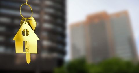 Golden house key with cityscape background symbolizing real estate