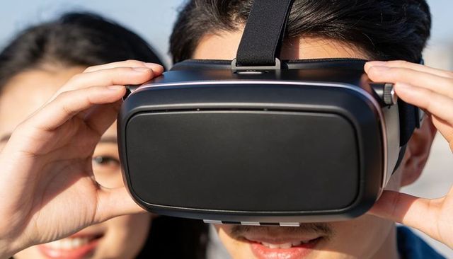 Young man adjusting vr headset while woman watches, virtual reality experience outdoors