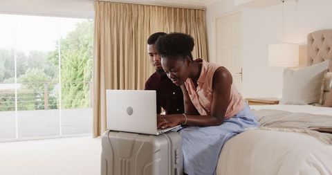 Young couple planning vacation with laptop in cozy bedroom