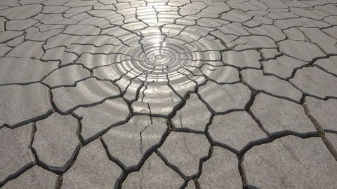 Ripples on sunlit cracked lakebed evoke drought and desert aesthetics