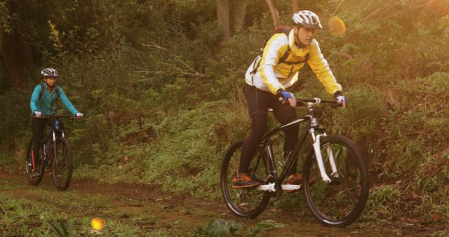 A man and girl cycle in sporty attire through a verdant forest trail, embodying active living. - Download Free Stock Photos Pikwizard.com