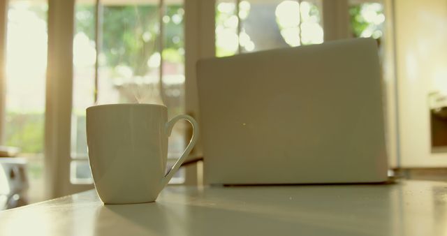 Steaming Coffee Mug and Laptop on Kitchen Table with Morning Sunlight - Download Free Stock Images Pikwizard.com