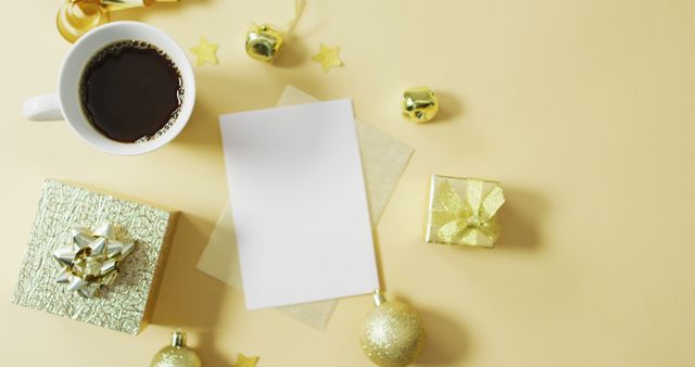 Image of gold christmas decorations with coffee and presents on yellow background. christmas, tradition and celebration concept.