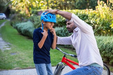 Father adjusting son's helmet in outdoor bonding moment