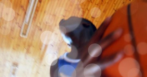 Teen basketball player holding ball close to camera with motion blur and warm gym bokeh