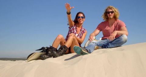 Carefree couple relaxing in sand dunes on sunny day