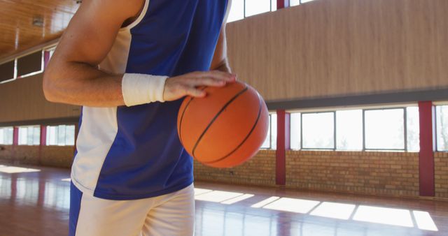 The athlete is engaged in a training session in an indoor basketball court, wearing a blue and white uniform. This can be used for themes related to sports, athletics, fitness, teamwork, or competitive activities.