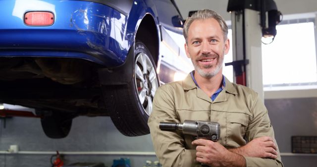 Mechanic standing with pneumatic wrench in garage 4k - Download Free Stock Photos Pikwizard.com