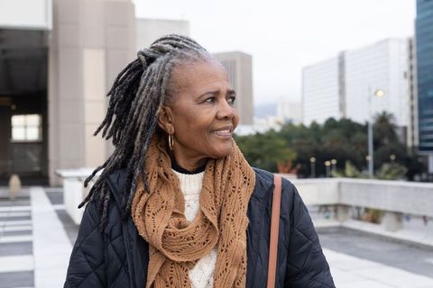 Senior african american woman enjoying urban rooftop view wearing cozy knitted scarf