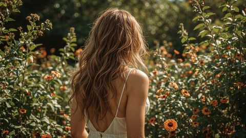 Beautiful lady in white sundress admiring vibrant flower garden