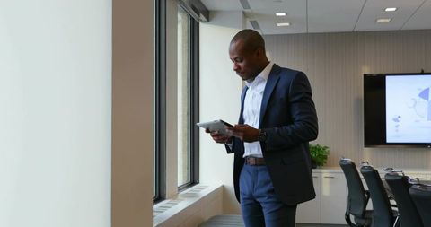 Business professional analyzing tablet in corporate meeting room