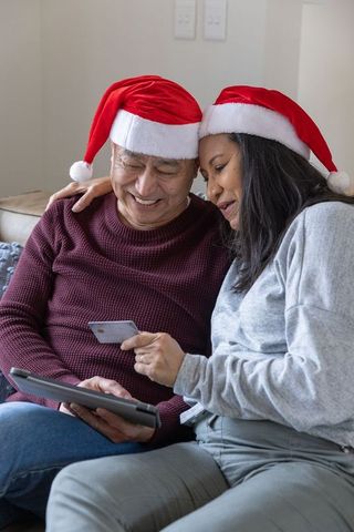 Asian Couple Relaxing with Tablet and Credit Card in Holiday Style