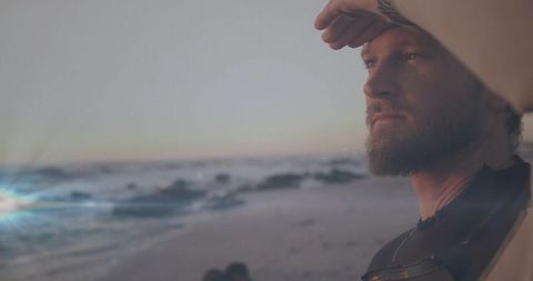 Surfer Scans Horizon at Sunset on Beach