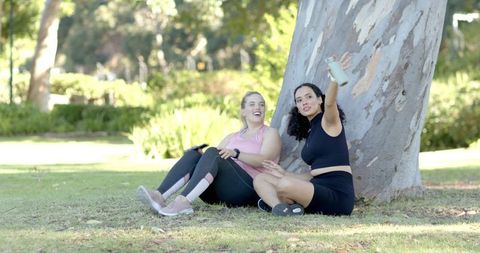 Female Friends Relaxing in Park with Water Bottle Looking Energized