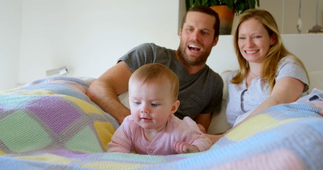 Happy family relaxing in bed with their baby - Download Free Stock Images Pikwizard.com