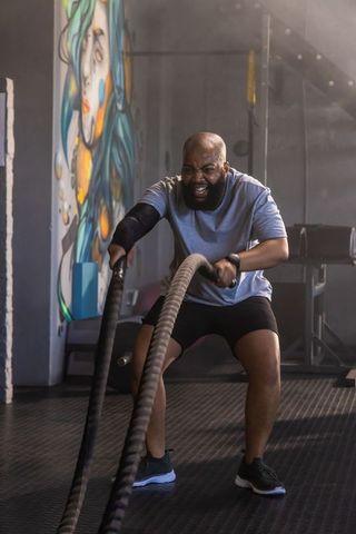 African american man crushing intense battle rope workout in urban gym strength training